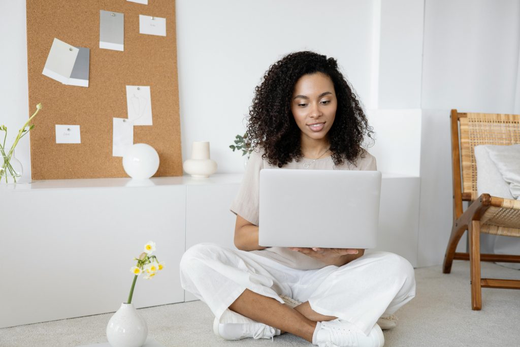 pexels-photo-7552374-7552374 Woman in White Dress Shirt and White Pants Sitting on Floor Using Macbook
